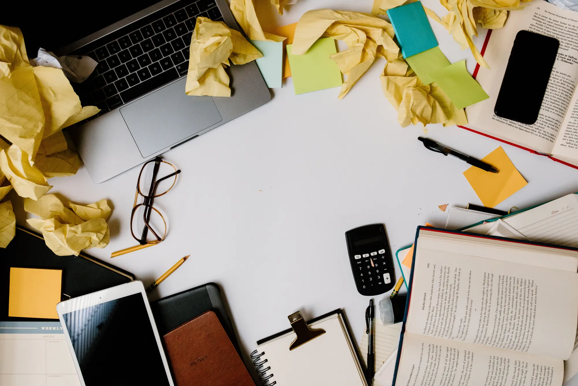 A cluttered desk covered in scrunched paper and notes, seen from above.